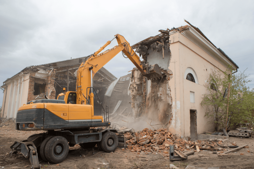 Il s'agit d'un chantier de démolition où l'ont voit une entreprise de maçonnerie spécialisée dans la démolition entrain de travailler. Un engin de destruction démolie un ancien bâtiment.